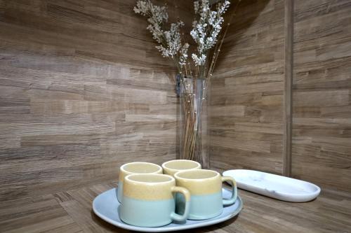 a table with three mugs and a vase with flowers at Marina Zeas Seaside Studio-MarinaQ in Piraeus