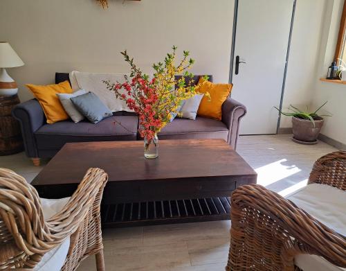 una sala de estar con una mesa con un jarrón de flores. en Relais saint vincent en Thonville
