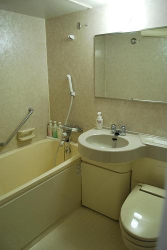 a bathroom with a sink and a toilet and a mirror at APA Hotel Suzuka-Chuou in Suzuka