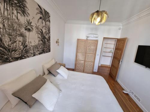 um quarto com uma grande cama branca e uma televisão em Appartement Enghien-les-Bains em Enghien-les-Bains