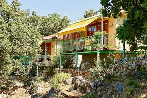 a yellow house with a balcony and a stone wall at Bio Guesthouse Mani Sonnenlink in Pírgos