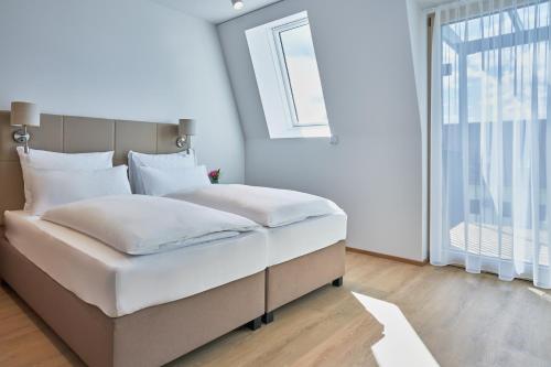 Aparthotel Bad Radkersburg في باد رادكرسبرغ: غرفة نوم مع سرير أبيض كبير مع نافذة