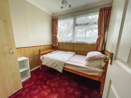 a small bedroom with a bed and a window at Superb Chalet In Nearby Hemsby Beach In Norfolk With Free Wifi Ref 00122ba in Hemsby