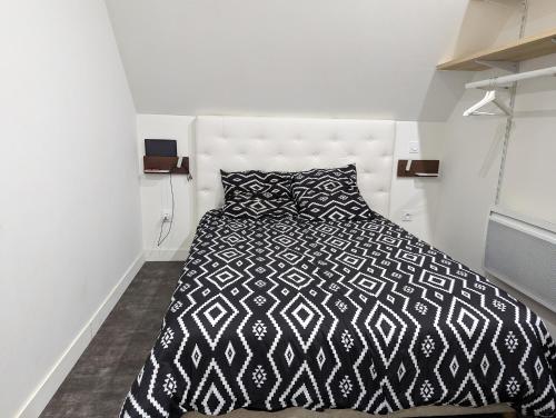 une chambre avec un lit avec une couette noire et blanche dans l'établissement Au bout de la rue, la MER wifi accès 24 sur 24 IPTV, à Sangatte