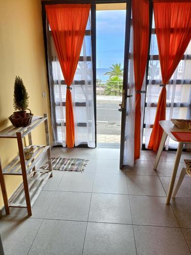 an open door with orange curtains and a view of the ocean at vista al mar. in Caleta de Interián