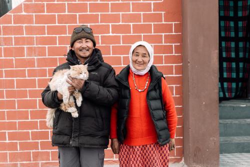 a man and a woman standing next to a brick wall at Astrostays at Pangong Lake in Spangmik