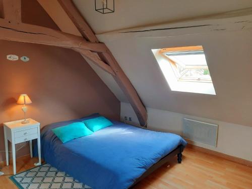 ein Schlafzimmer mit einem blauen Bett und einem Dachfenster in der Unterkunft La Ferme Neuve in Fillé
