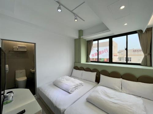 a bedroom with a bed with white sheets and a window at Planet 23 in Chiayi City