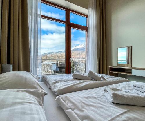 two beds in a room with a large window at Hotelový apartmán ALFRED C407 in Smokovce