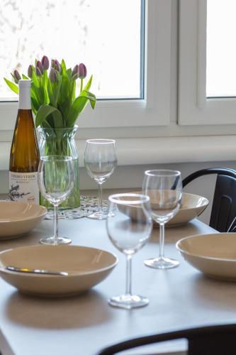 a table with wine glasses and a vase with flowers at Seaside Escape Pet Friendly Apartments Mielenko by Noclegi Renters in Mielenko