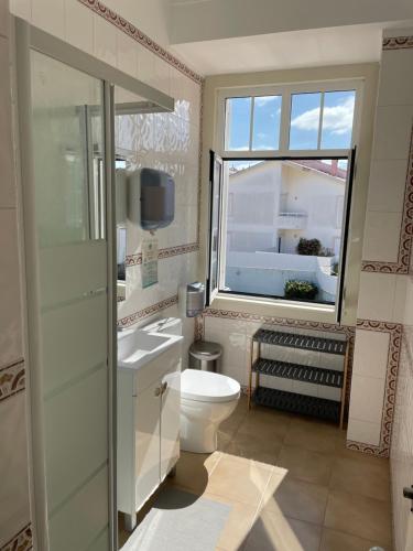a bathroom with a white toilet and a window at Impact Beach House in Estoril