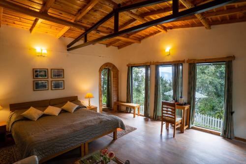 a bedroom with a bed and large windows at Avenida Himalayan Retreat in Mukteswar