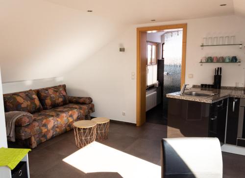 a living room with a couch and a kitchen at Baumeister`s Ferienwohnung 