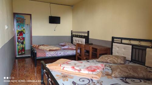a room with three beds and a table and a television at Tengger Indah Bromo by ABM in Bromo