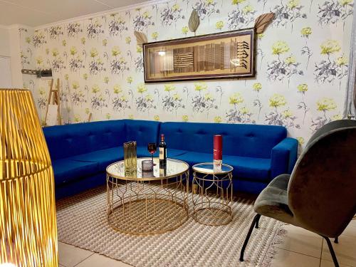 - un salon avec un canapé bleu et 2 tables dans l'établissement Idesel Apartment, à Edendale