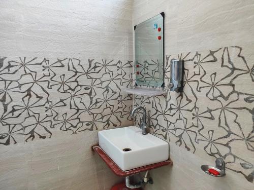 STAYMAKER Madhuwan Heights في Bokāro: حمام مع حوض ومرآة على الحائط