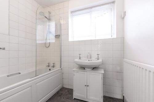 Deepdene Close في ريدينغ: حمام أبيض مع حوض وحوض استحمام ومغسلة