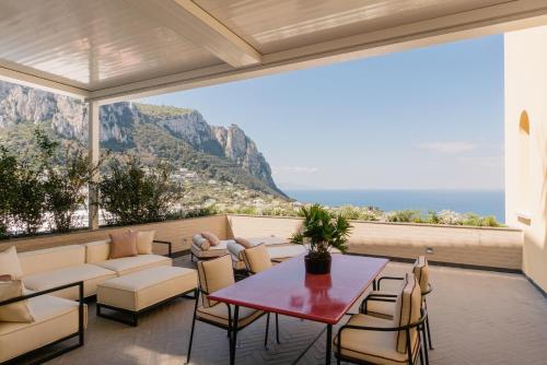 Palazzo M Capri في كابري: فناء مع طاولة وكراسي وإطلالة على المحيط