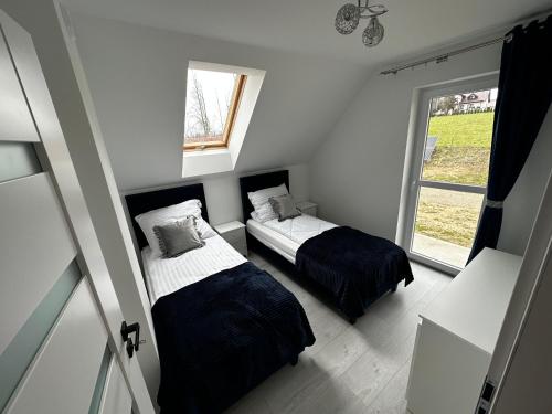 a small bedroom with two beds and a window at Agroturystyka Parcele 