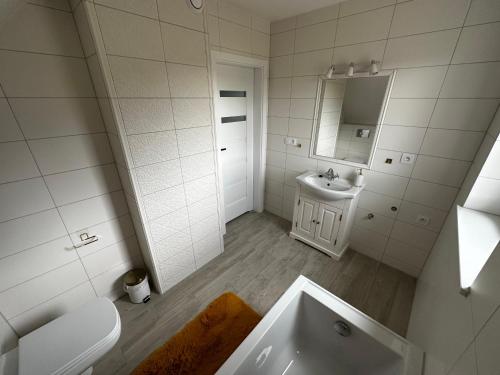 La salle de bains blanche est pourvue d'une baignoire et d'un lavabo. dans l'établissement Agroturystyka Parcele, 