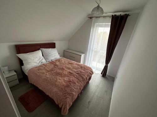 a bedroom with a bed with a brown blanket and a window at Agroturystyka Parcele-696-779-886- in Krajno
