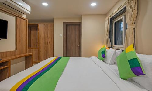 a bedroom with a large white bed with colorful pillows at Treebo Gyani's in Jamshedpur