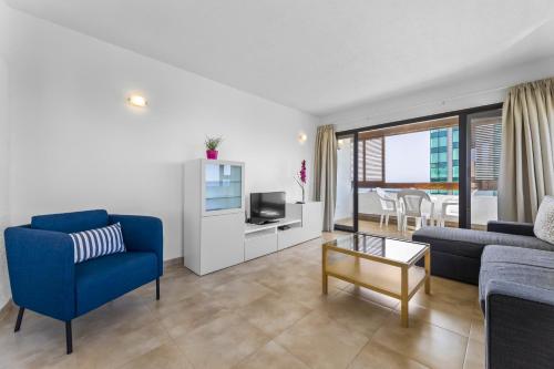 sala de estar con sofá azul y TV en Apartamentos Arrecife Playa, en Arrecife
