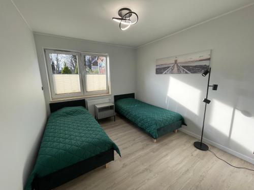 een slaapkamer met 2 groene bedden en een lamp bij Apartamenty Rodzina nad morzem in Gdańsk