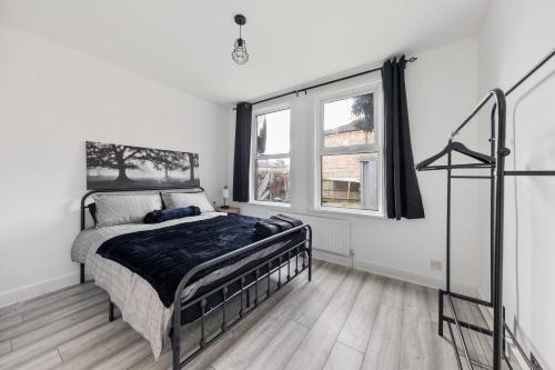 a bedroom with a bed and two windows at Beautifully Modern 2-Bed Apartment w/garden in London