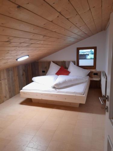 a bedroom with a bed with white sheets and red pillows at Wildauhof - Bauernhaus in Fügenberg