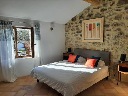 1 dormitorio con 1 cama con almohadas de color naranja y azul en Bastide du Barry - Centre historique de Vallon Pont d'arc, en Vallon-Pont-dʼArc