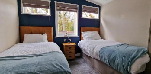 two beds in a room with two windows at Stunning Lodge With Large Decking At Azure Seas In Suffolk Ref 32109og in Lowestoft