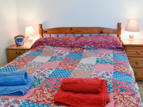 Una cama con un edredón rojo y azul. en Chywoon en St Just
