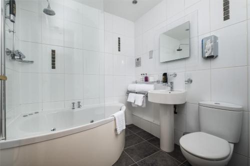 a white bathroom with a tub and a toilet and a sink at The Howbeck & The Retreat Central location, incl off-site Health Club and parking EV point available, GREAT DEALS ON in Windermere