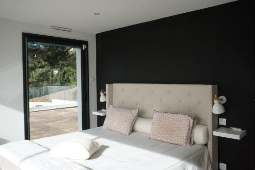a bedroom with a white bed with a black wall at ® L'imprenable - Somptueuse villa vue mer in Marseille
