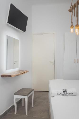 a room with a bed and a stool and a tv at Alpha & Omega in Karpathos Town