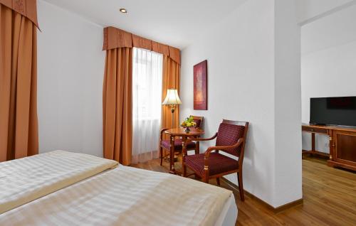 a hotel room with a bed and a table and chairs at Hotel Continental in Mariánské Lázně