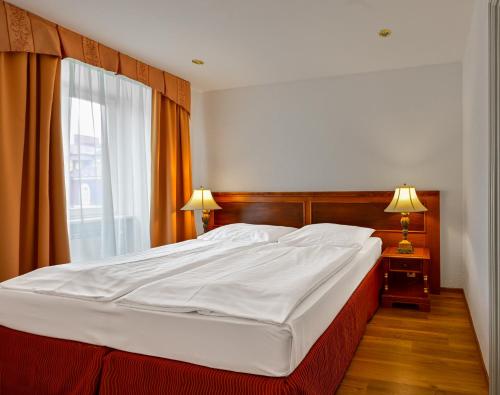 a large white bed in a bedroom with a window at Hotel Continental in Mariánské Lázně
