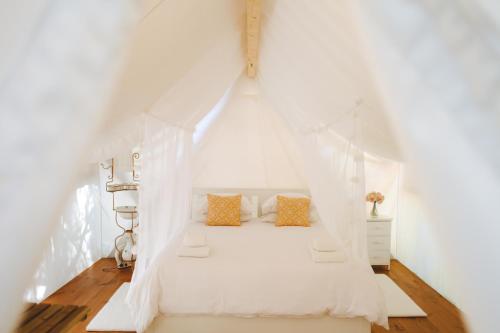 1 dormitorio con 1 cama blanca con dosel en Kabaceira Glamping en Atalaia