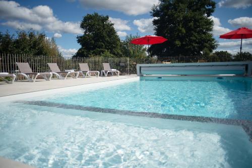 a swimming pool with chairs and umbrellas at Le jardin des 4 saisons in Le Mans