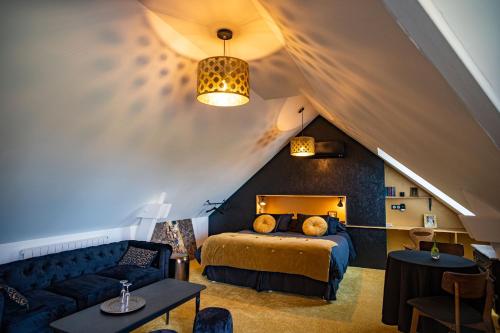 ein Schlafzimmer mit einem Bett und einem Sofa im Dachgeschoss in der Unterkunft Le jardin des 4 saisons in Le Mans