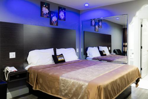 a bedroom with two beds with blue walls and mirrors at Downtowner Inns - Houston Downtown & Convention Center in Houston