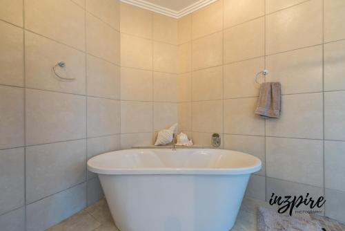 uma banheira branca numa casa de banho com azulejos brancos em Gouriqua 401 em Mossel Bay
