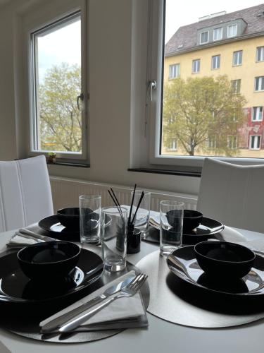 una mesa con placas y utensilios negros y una ventana en Apartment Vienna - Contactless Check-In, en Viena