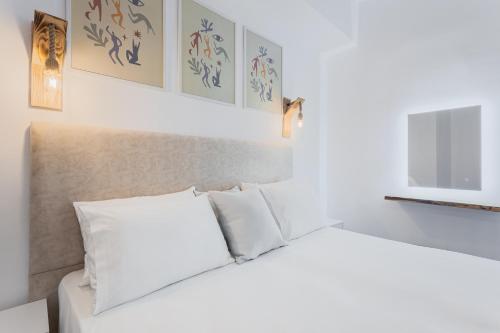 een wit bed met witte kussens in een kamer bij Alpha & Omega in Karpathos