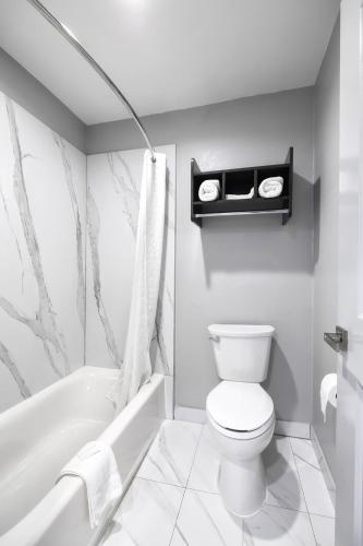 a white bathroom with a toilet and a bath tub at Downtowner Inns - Houston Downtown & Convention Center in Houston