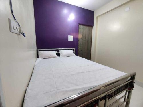 a large bed in a room with a purple wall at OYO The Pine & Dine in Sonpur