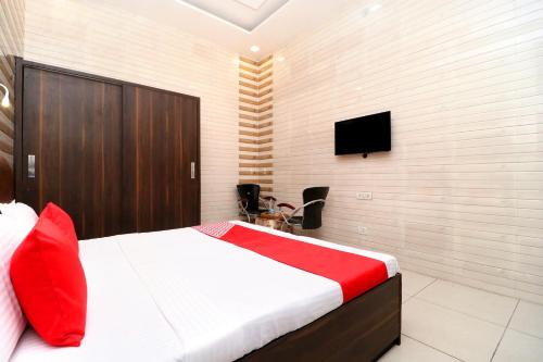 a bedroom with a bed and a tv on the wall at Hotel O Max in Jalandhar