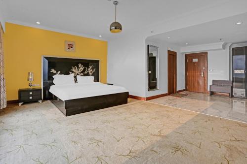 1 dormitorio grande con 1 cama grande y paredes amarillas en Townhouse Royal Palms Shared Serviced Apartment, en Bombay