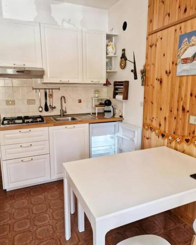 a kitchen with white cabinets and a white table at Scoiattolo Apartment in San Martino di Castrozza